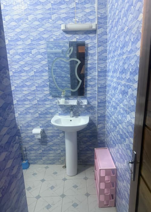 Salle de bain moderne au Keur Medzo Lac Rose avec carrelage bleu, lavabo sur piédestal et miroir à Niaga, Sénégal