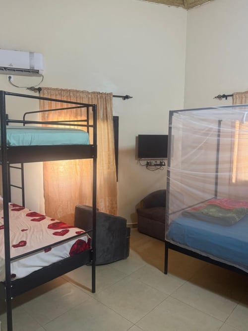 Chambre du dortoir Keur Medzo Lac Rose avec deux lits superposés en métal noir, moustiquaires et télévision à Niaga, Sénégal