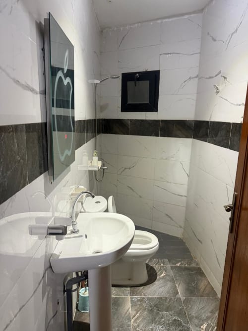 Salle de bains moderne de la chambre Gorée 2 à l'hôtel Keur Medzo, Lac Rose Niaga, avec lavabo sur colonne, toilettes et carrelage en marbre