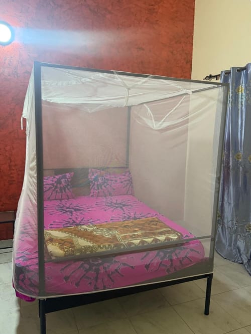 Lit à quatre colonnes avec voile anti-moustiques et parure de lit à motifs rose à l'hôtel Keur Medzo à Lac Rose, Niaga, Sénégal