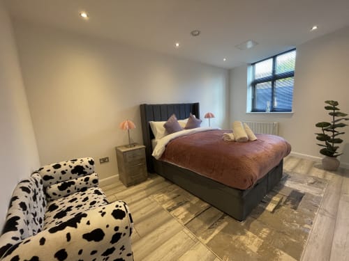Modern bedroom in Empire Serviced Apartments Leicester with king bed, dalmatian chair, and city views from large window