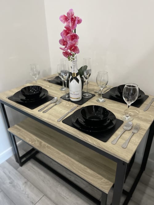 Elegant dining setup at Empire Serviced Apartments Leicester with black place settings, pink orchid centerpiece, and