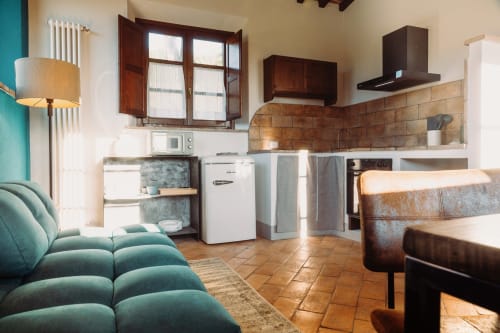 Cucina moderna e zona living nella stanza La Vigna di Agriturismo Il Serraglio a Montepulciano con divano turchese