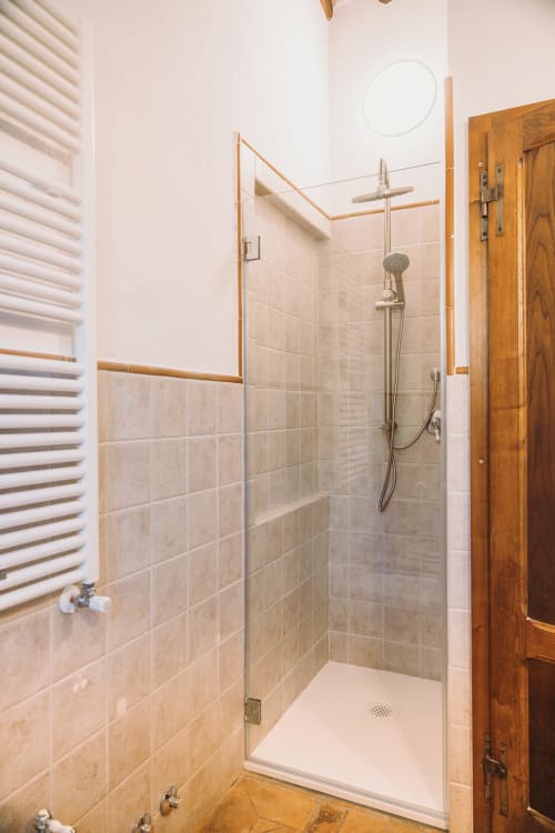 Doccia moderna con cabina in vetro e soffione a pioggia nella camera La Vigna dell'Agriturismo Il Serraglio