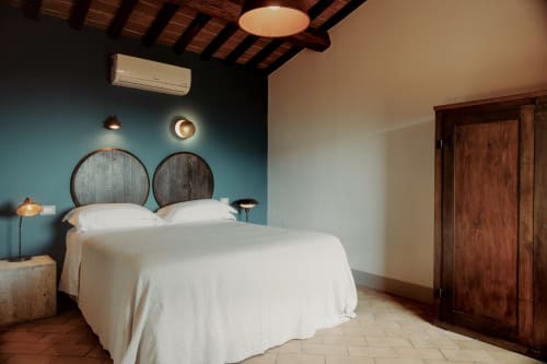 Camera moderna presso l'Agriturismo Il Serraglio con parete azzurra, testata in legno, biancheria bianca e stile rustico toscano