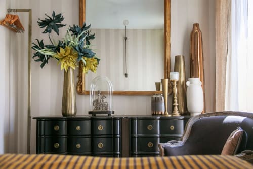 Commode noire avec vases en laiton doré et fleurs dans l'appartement L'ALCÔVE du gîte Alombre Lectoure
