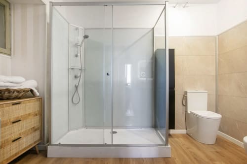 Salle de bain moderne avec douche vitrée, toilettes et meuble-lavabo en bois à l'Alombre B&B de Lectoure