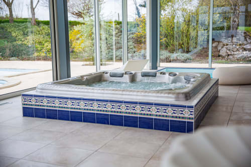 Luxueux bain à remous avec carrelage bleu dans l'espace spa de la Villa Bianca, donnant sur le jardin