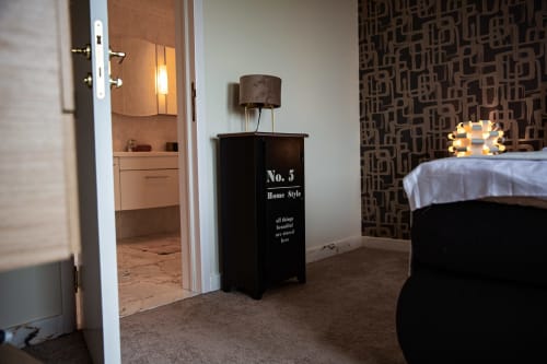 Chambre moderne de la Villa Bianca avec lit, entrée de la salle de bain, papier peint à motifs et collection de parfums d'intérieur