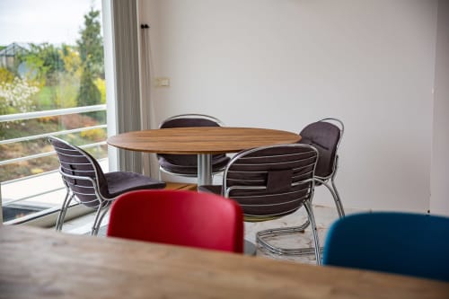 Salle à manger moderne à la Villa Bianca avec table ronde en bois, chaises noires et vue sur le jardin