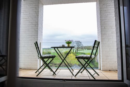 Vue depuis la chambre Villa Bianca : table et chaises sur la terrasse dominant les champs verts de Mortroux Dalhem, Belgique