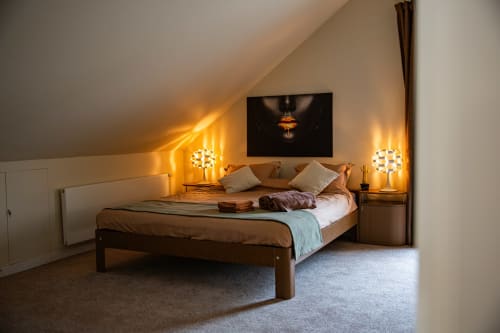Luxueuse chambre double à la Villa Bianca avec lit en bois, éclairage chaleureux, télévision écran plat et vue sur le jardin à Mortroux Dalhem