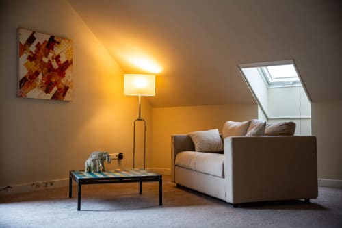 Chambre double luxe à la Villa Bianca avec canapé beige, lampadaire, table basse et lucarne à Mortroux Dalhem