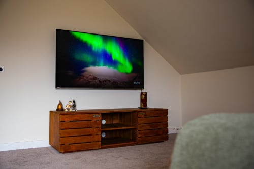 Télévision murale affichant les aurores boréales au-dessus d'une console média en bois dans la chambre de luxe de la Villa Bianca, Belgique