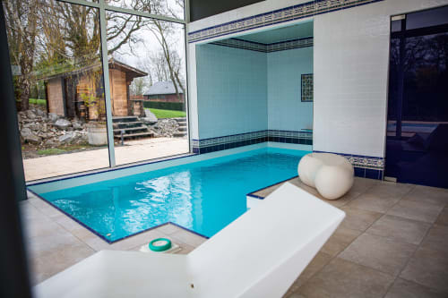 Piscine intérieure de la Villa Bianca, luxueux B&B à Mortroux Dalhem, avec carrelage turquoise et vue sur le jardin
