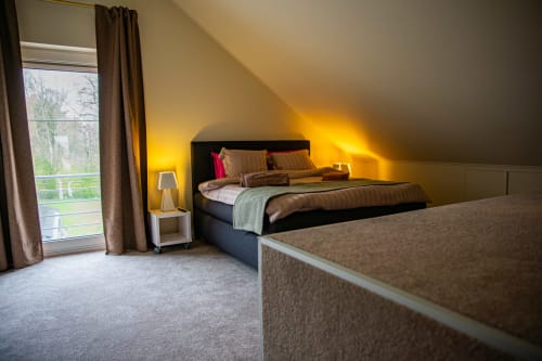 Chambre moderne à la Villa Bianca avec lit double, éclairage chaleureux, vue sur jardin depuis les portes-fenêtres et mobilier contemporain