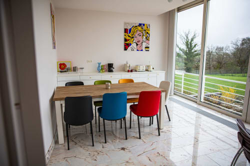Salle à manger moderne de la Villa Bianca avec chaises colorées, table en bois, vue sur le jardin par les portes vitrées et décor pop art