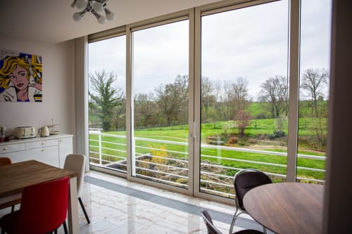 Salle à manger Villa Bianca avec vue sur le jardin et paysage champêtre belge à travers les grandes portes vitrées