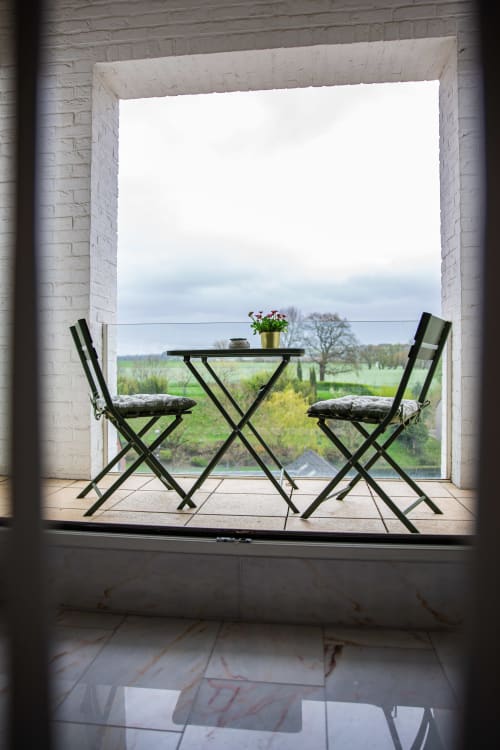 Espace terrasse de Villa Bianca avec vue sur le jardin, chaises noires, petite table fleurie surplombant la campagne