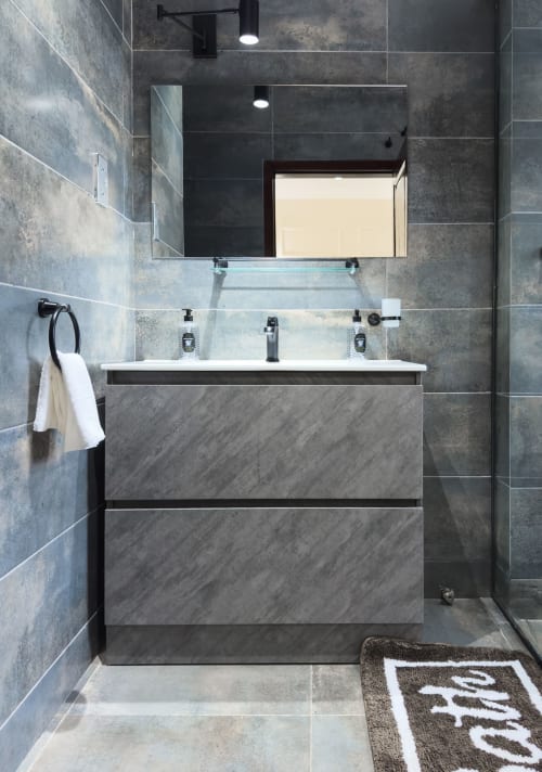 Modern bathroom in Capella Unit 4 at Cozy Apartments Ghana with gray tile walls, floating vanity, mirror, and rainfall