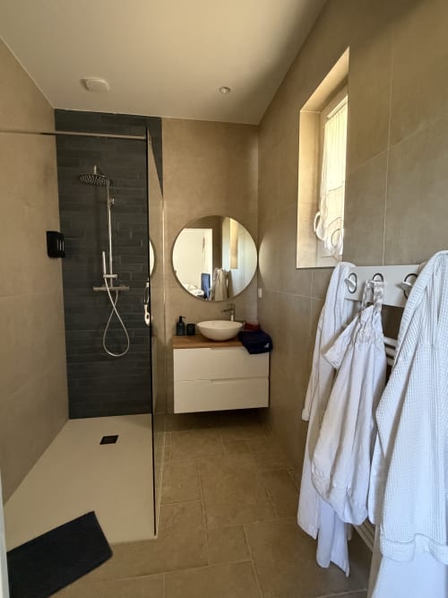 Salle de bain moderne de la chambre Le nid des anges au Petit Coin de Paradis B&B à Alata, avec douche à l'italienne, miroir rond et finitions blanches