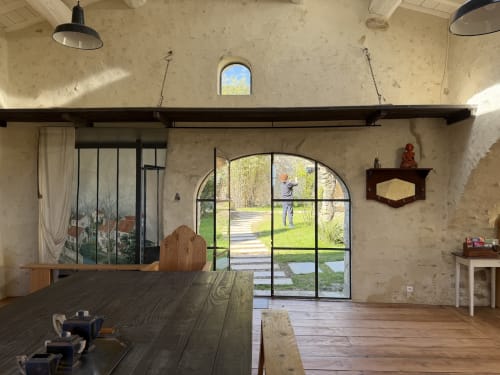 Salle à manger rustique à La Grange Neuve avec baies vitrées en arc surplombant les jardins de Potélières