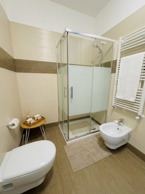 Modern bathroom at B&B Alba in Polignano a Mare with glass shower enclosure, white toilet and bidet, heated towel rack, and