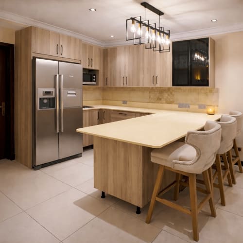 Modern kitchen in Capella Unit 4 at Cozy Apartments Ghana with wood cabinets, stainless steel appliances, island seating, and