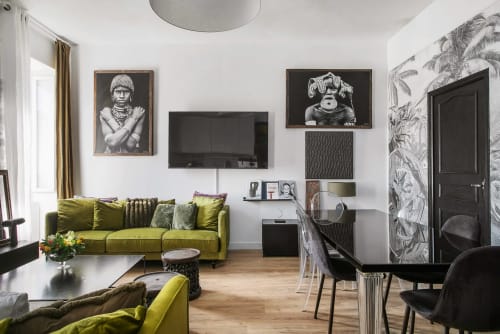Salon moderne de l'Alombre BnB à Lectoure : canapé vert citron, TV murale, œuvres d'art noir et décor contemporain