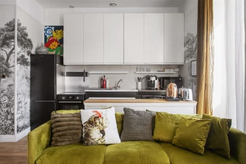Cuisine moderne du gîte Alombre avec meubles blancs, appareils noirs, plan de travail bois et canapé vert olive à Lectoure