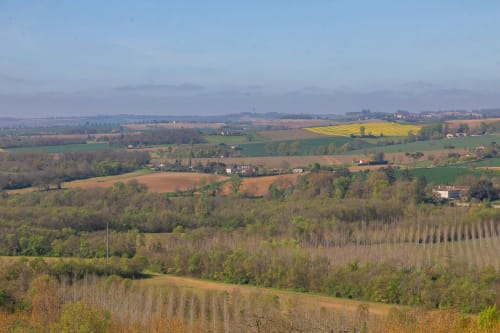 Vue panoramique de la campagne depuis Alombre B&B à Lectoure : collines ondulantes, terres agricoles et villages éparpillés.