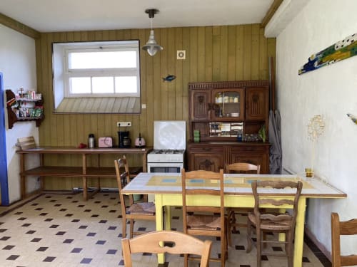 Dining room in Le Gîte de la Fresque Interdite cottage at Le Lama Zébré, Penmarch with wooden table and chairs, yellow bench
