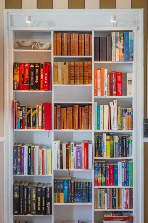 Bibliothèque intégrée blanche avec livres organisés et objets décoratifs dans l'appartement L'Aparté à Alombre B&B, Lectoure, France