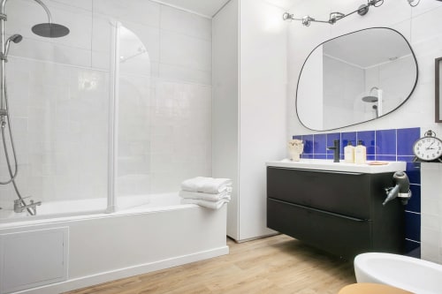 Salle de bain moderne du studio L'APARTÉ à l'Alombre B&B, Lectoure, avec vanité noire, miroir ovale, douche et carrelage bleu