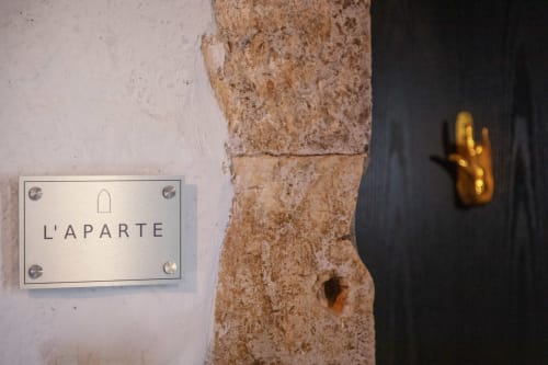 Pancarte de la chambre L'Aparté à l'Alombre B&B à Lectoure, France, avec mur de pierre rustique et poignée de porte dorée