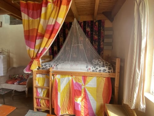 Colorful canopy bed in shared dorm room at Le Lama Zébré, Penmarch - cozy accommodation with mosquito net and striped