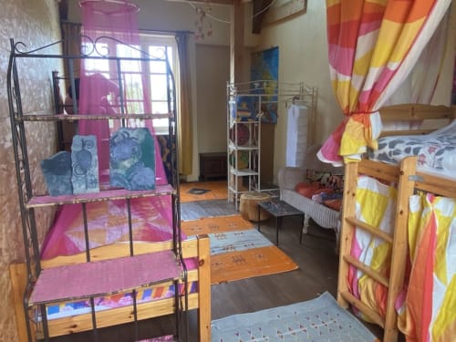 Colorful shared dormitory bedroom at Le Lama Zébré in Penmarch with bunk beds and rainbow curtains