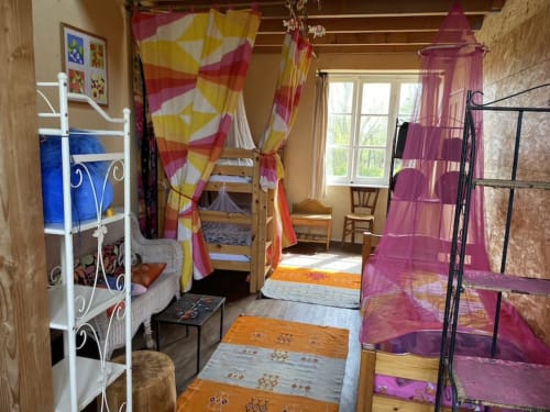 Colorful shared dorm room at Le Lama Zébré in Penmarch with canopy beds, garden views, and bright curtains