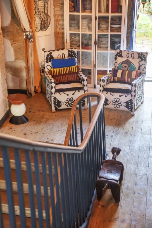 Cozy sitting room at Alombre B&B in Lectoure with decorative patterned armchairs, striped cushions, and rustic wooden floors