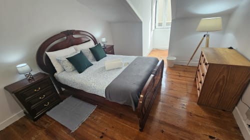 Quarto no hostel Grupo Lisboa Alojamentos em Lisboa com cama de madeira, mesinhas de cabeceira, cómoda e luminária com vista para a cidade