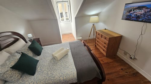 Acomodação aconchegante no hostel de Lisboa com cama de casal, almofadas verdes, cômoda em madeira, TV e vista para a cidade do Quarto 10 Garden 2