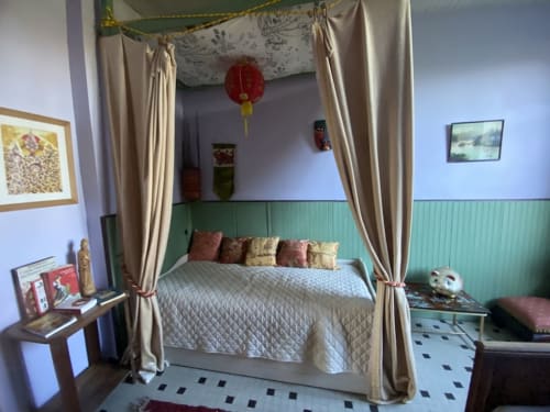Chinese-themed bedroom with canopy bed at Le Lama Zébré B&B, Penmarch. Turquoise walls, red lantern, decorative pillows.