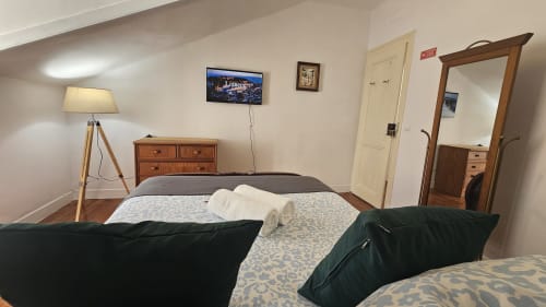 Quarto moderno de albergue em Lisboa com camas geminadas, móveis de madeira, TV, luminária de piso e vista da cidade no Grupo Lisboa Alojamentos