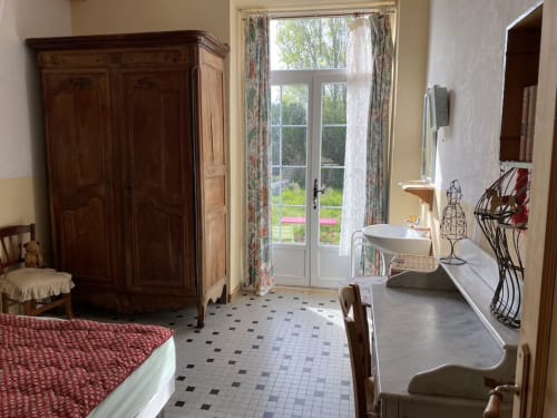Spacious bedroom at Le Lama Zébré BnB in Penmarch with wooden wardrobe, garden view doors, and en-suite sink