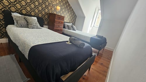 Quarto aconchegante na Grupo Lisboa Alojamentos com cama, criado-mudo em madeira, papel de parede estampado e piso em madeira em Lisboa