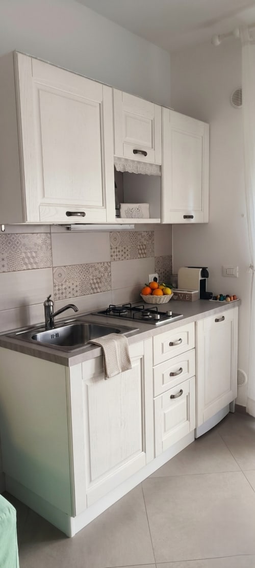 Cucina bianca moderna con fornello a gas, lavello e piastrelle decorate al B&B Alba di Polignano a Mare