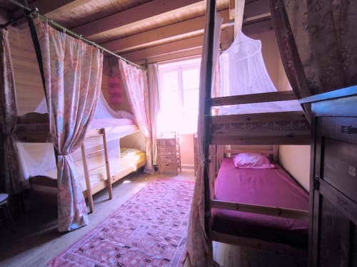 Girls' shared dorm room with pink-lit bunk beds and sheer curtains at Le Lama Zébré, Penmarch