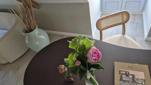 Elegante eettafel in het appartement L'Arbre Voyageur bij Moulin Renaudiots Autun, met roze pioenrozen en rieten stoel