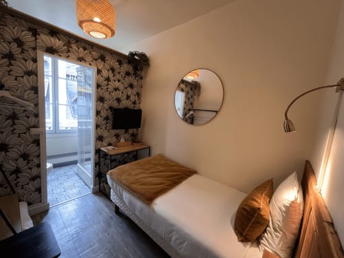 Cozy single room at Hotel Le Trouville with floral wallpaper, round mirror, city view, and warm brown bedding