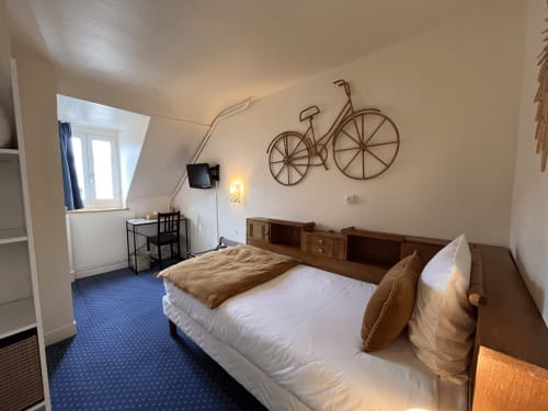 Single room at Hotel Le Trouville with double bed, desk, bicycle wall art, and city view window in Trouville sur Mer.
